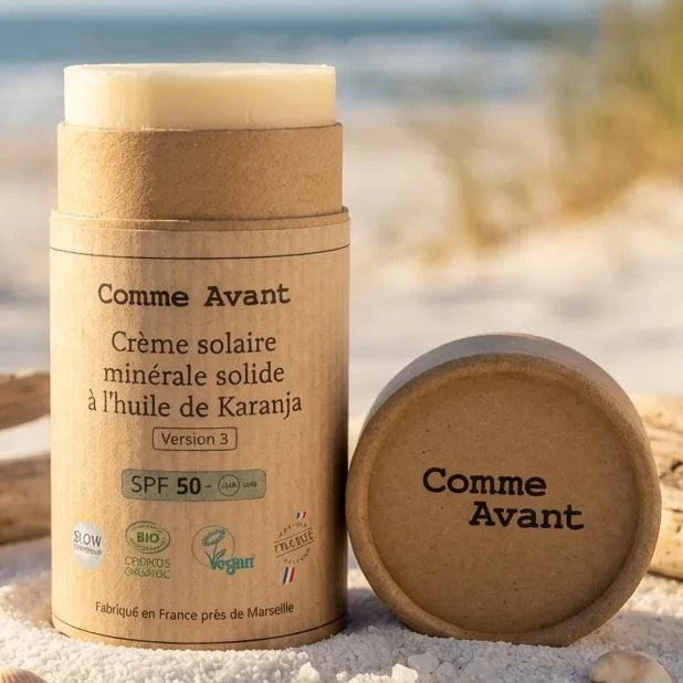 Crème solaire minérale solide SPF50 Comme Avant avec packaging bois sur plage ensoleillée