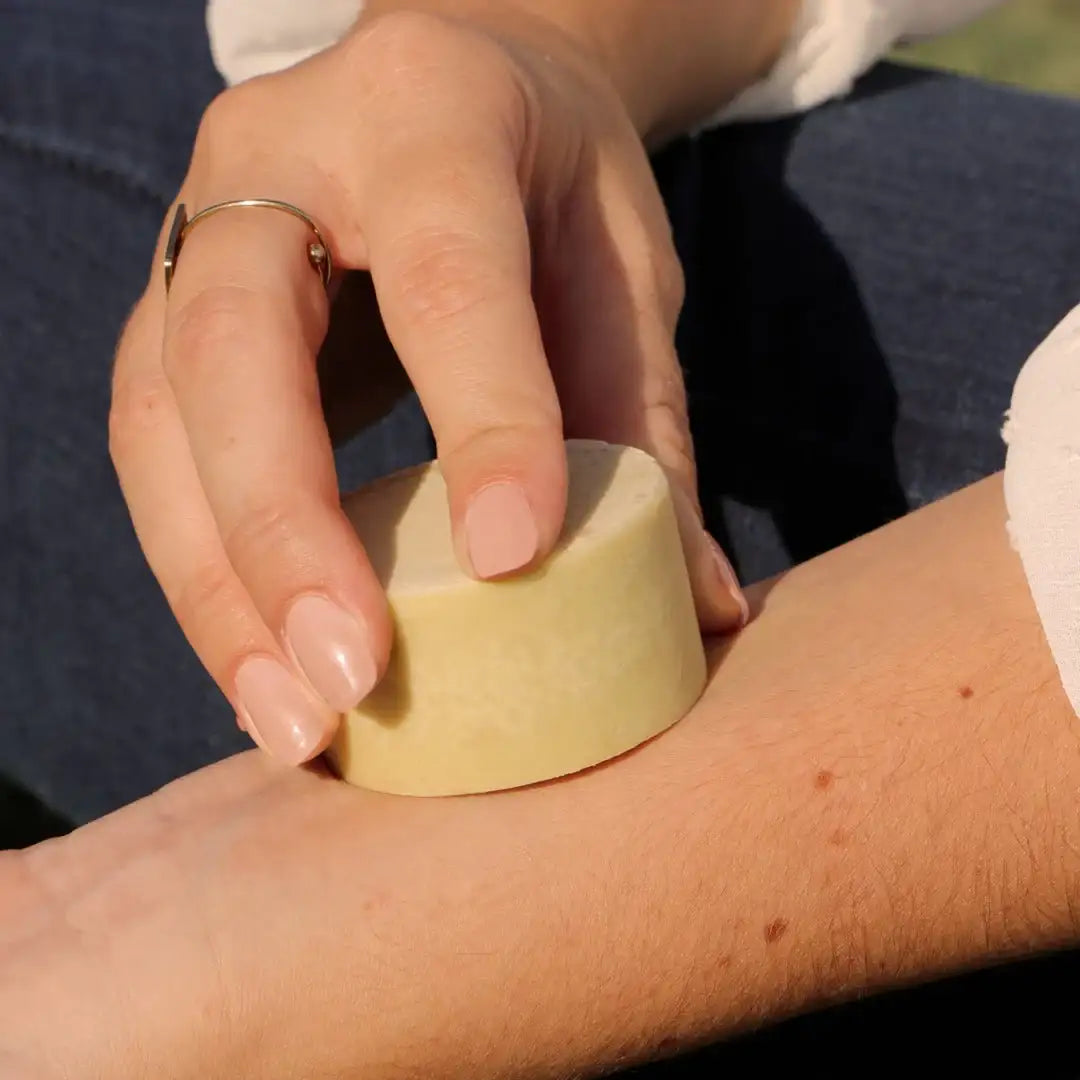 Une personne en train d'appliquer sur son avant-bras de la crème solide au macérât de plantain anti-démangeaisons de la marque Comme Avant