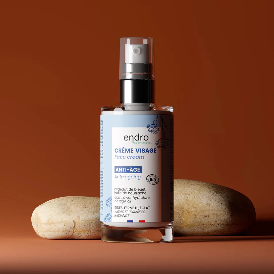 Un flacon de crème anti-âge de la marque Endro devant des galets