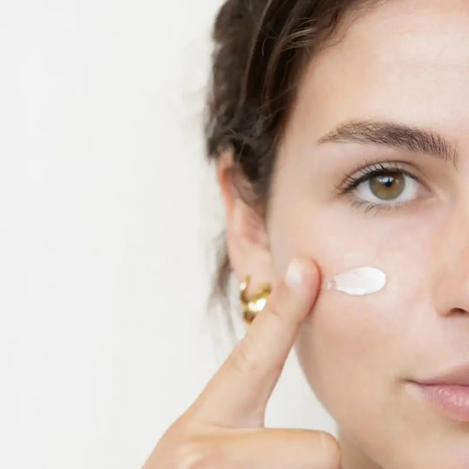 Une femme appliquant de la crème visage hydratante