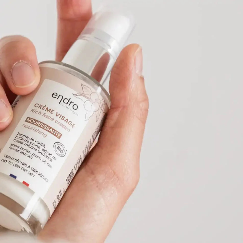 Un flacon de crème visage nourrissante de la marque Endro tenu dans une main 
