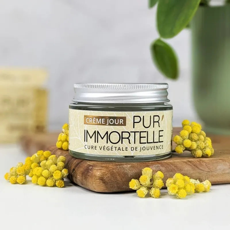 Un pot de Crème Visage Jour bio Pur'Immortelle de 50ml de la marque Propos'Nature, sur un rondin en bois