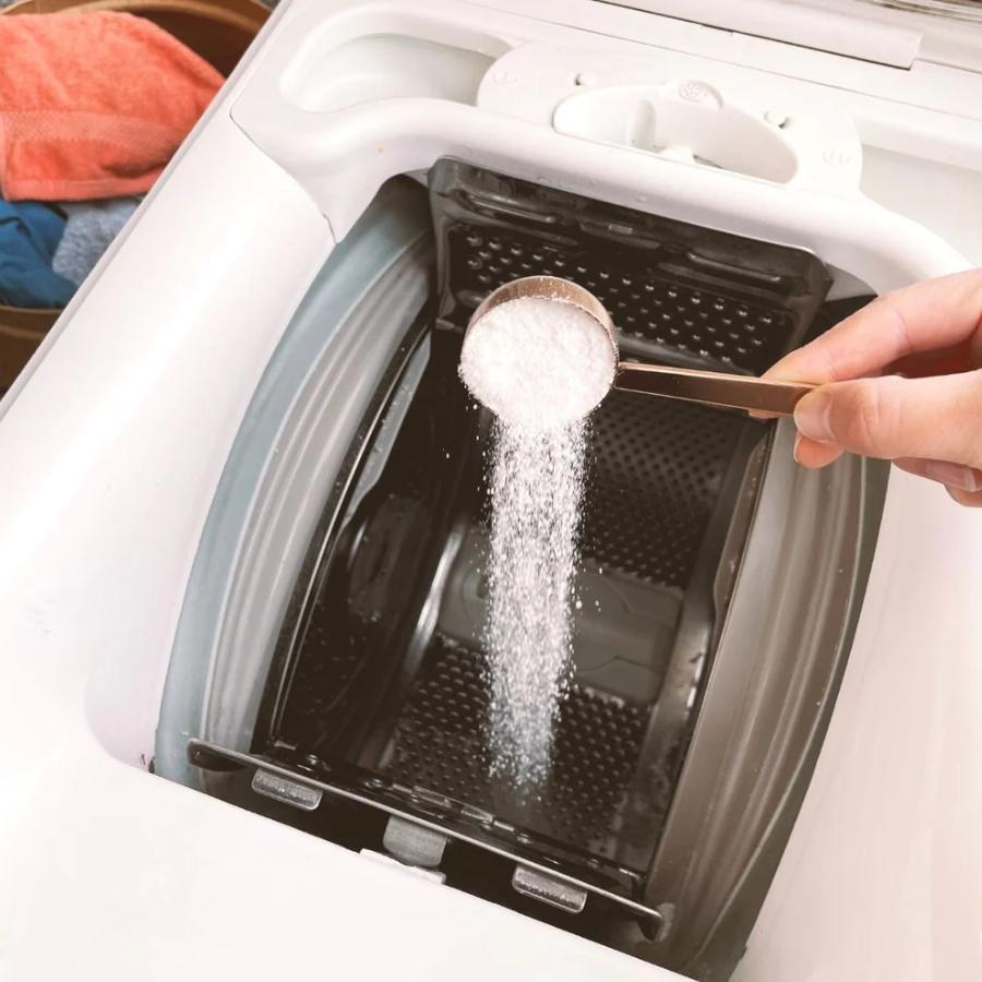 Cuillère doseuse Pimpant versant de la lessive en poudre dans le bac d’une machine à laver