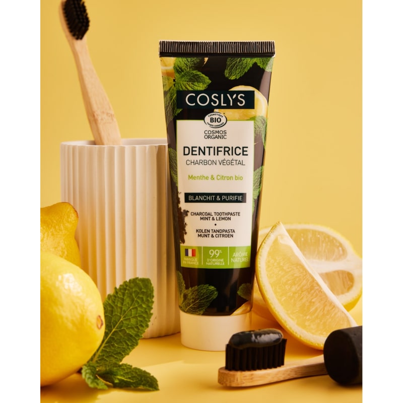 Un dentifrice au charbon végétal bio de 100 g de la marque Coslys dans une ambiance jaune faisant penser au citron