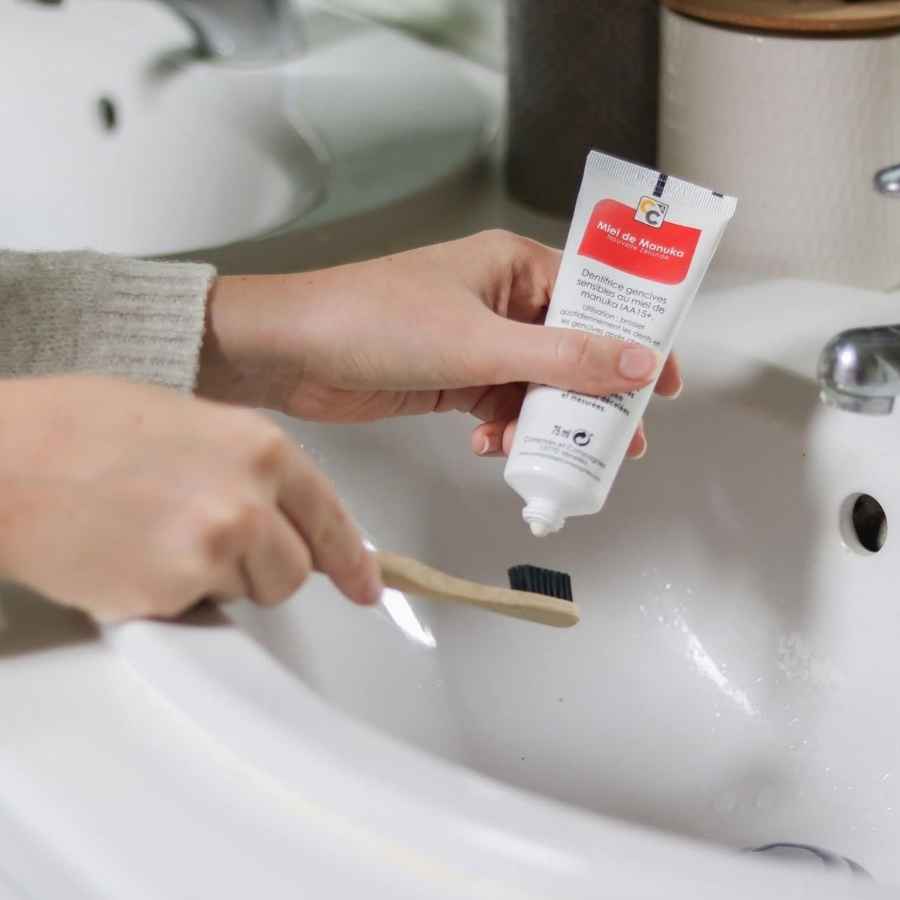 Zoom sur une personne en train d'étaler du dentifrice bio pour gencives sensibles au miel de manuka de la marque Comptoirs et compagnies, sur une brosse à dents