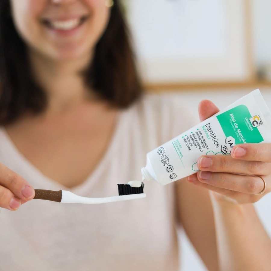 Une personne en train d'étaler sur une brosse à dent du dentifrice blancheur au miel de manuka de la marque Comptoirs et compagnies
