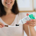 Une personne en train d'étaler sur une brosse à dent du dentifrice blancheur au miel de manuka de la marque Comptoirs et compagnies