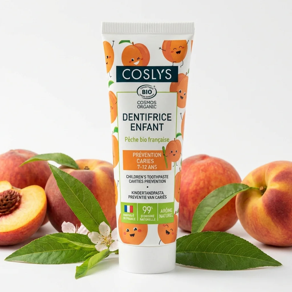 Dentifrice enfant Pêche bio Coslys 50ml avec pêches et feuilles vertes sur fond blanc