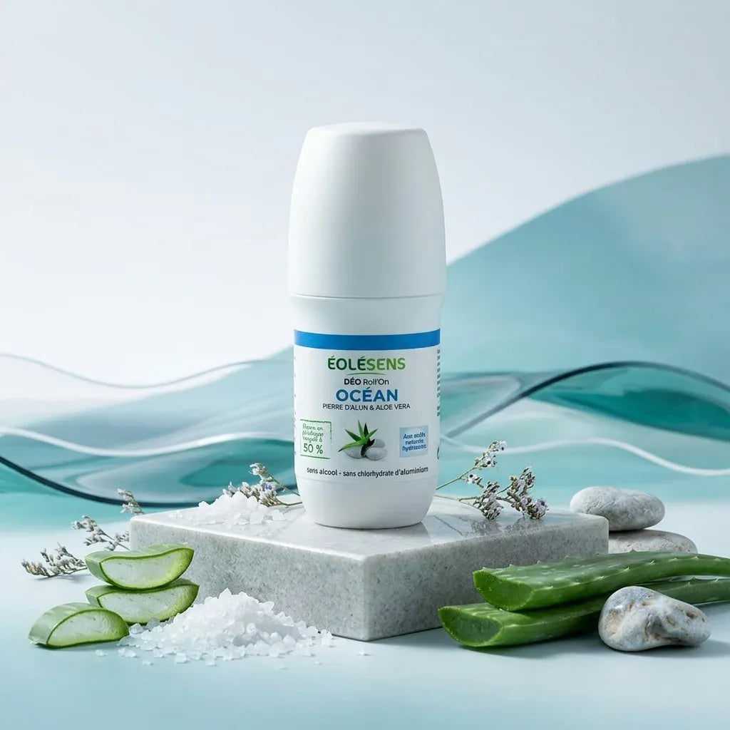 Déodorant bio Eolesens parfum Océan, roll-on blanc avec bande bleue et logo vert, entouré de cristaux de sel marin et feuilles d'aloé vera