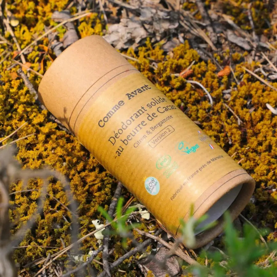 Un Déodorant Solide de 50g au beurre de cacao citron et bergamote de la marque Comme avant sur un lit de fleurs