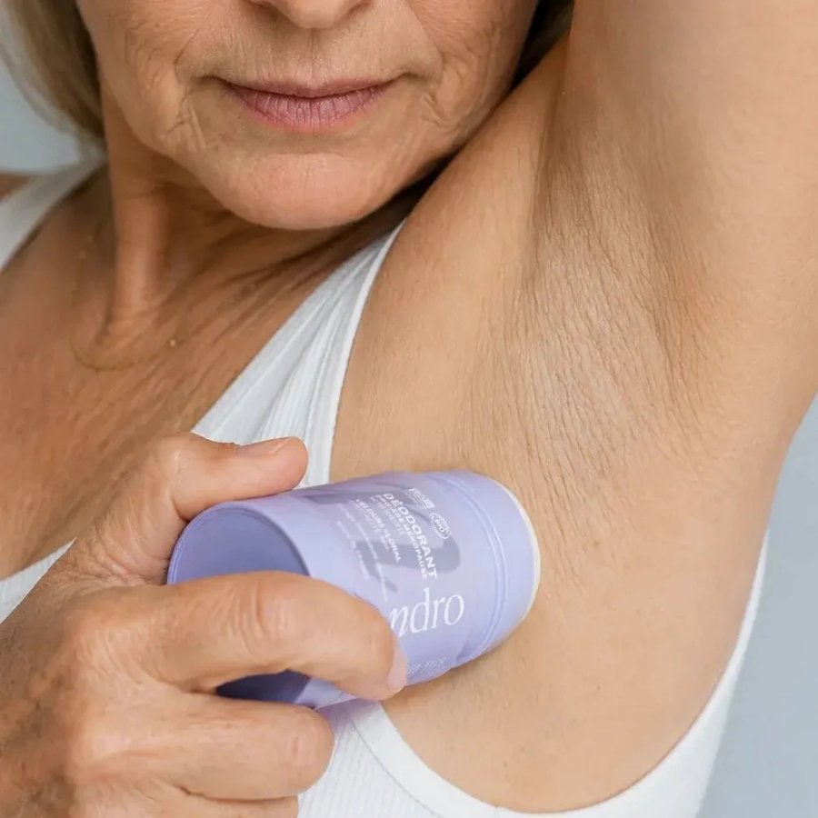Femme appliquant un déodorant stick Endro Pro-âge ménopause sous l’aisselle, pour montrer son utilisation au quotidien.