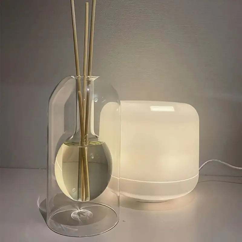 Un diffuseur de parfum en verre soufflé posé à côté d'une lampe