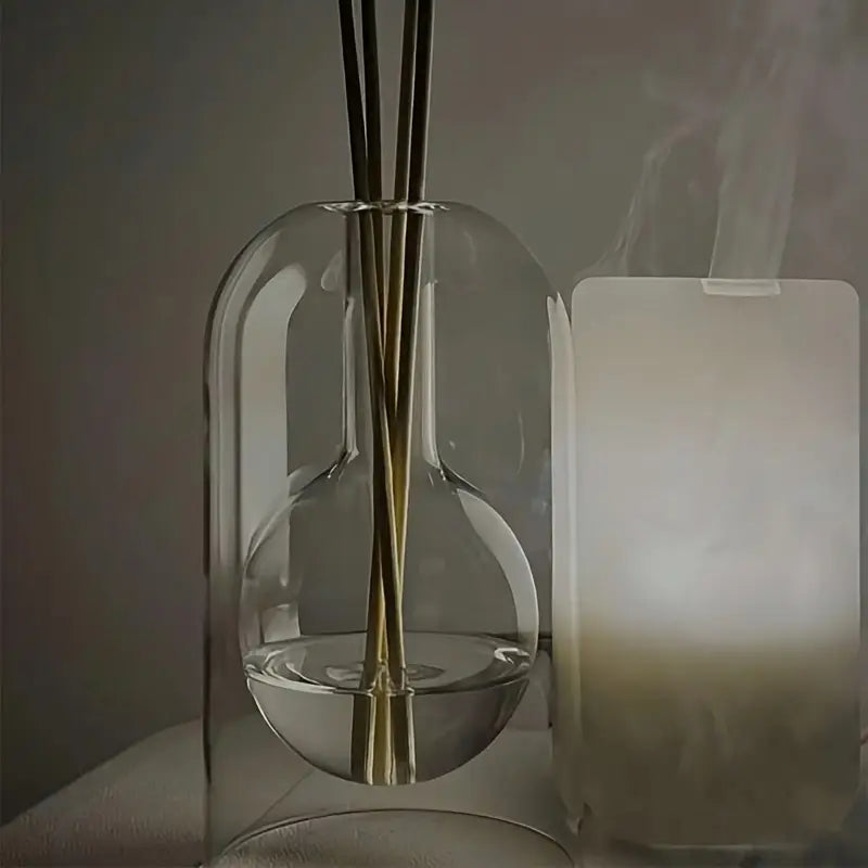 Un diffuseur de parfum en verre soufflé posé à côté d'un lampe d'aromathérapie