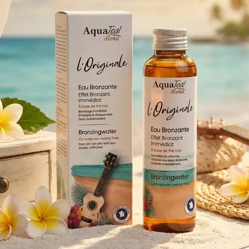 Eau Bronzante l'Originale Aquatéal en packaging luxe sur vanity côtière avec fleurs tropicales