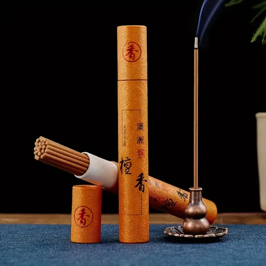 Deux boîtes d'encens dont une ouverte posée sur son couvercle et un bâton d'encens en combustion