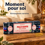 Encens Satya Palo Santo 15g dans sa boîte, à côté d'un porte-encens fumant, sur une table en bois dans une ambiance méditative