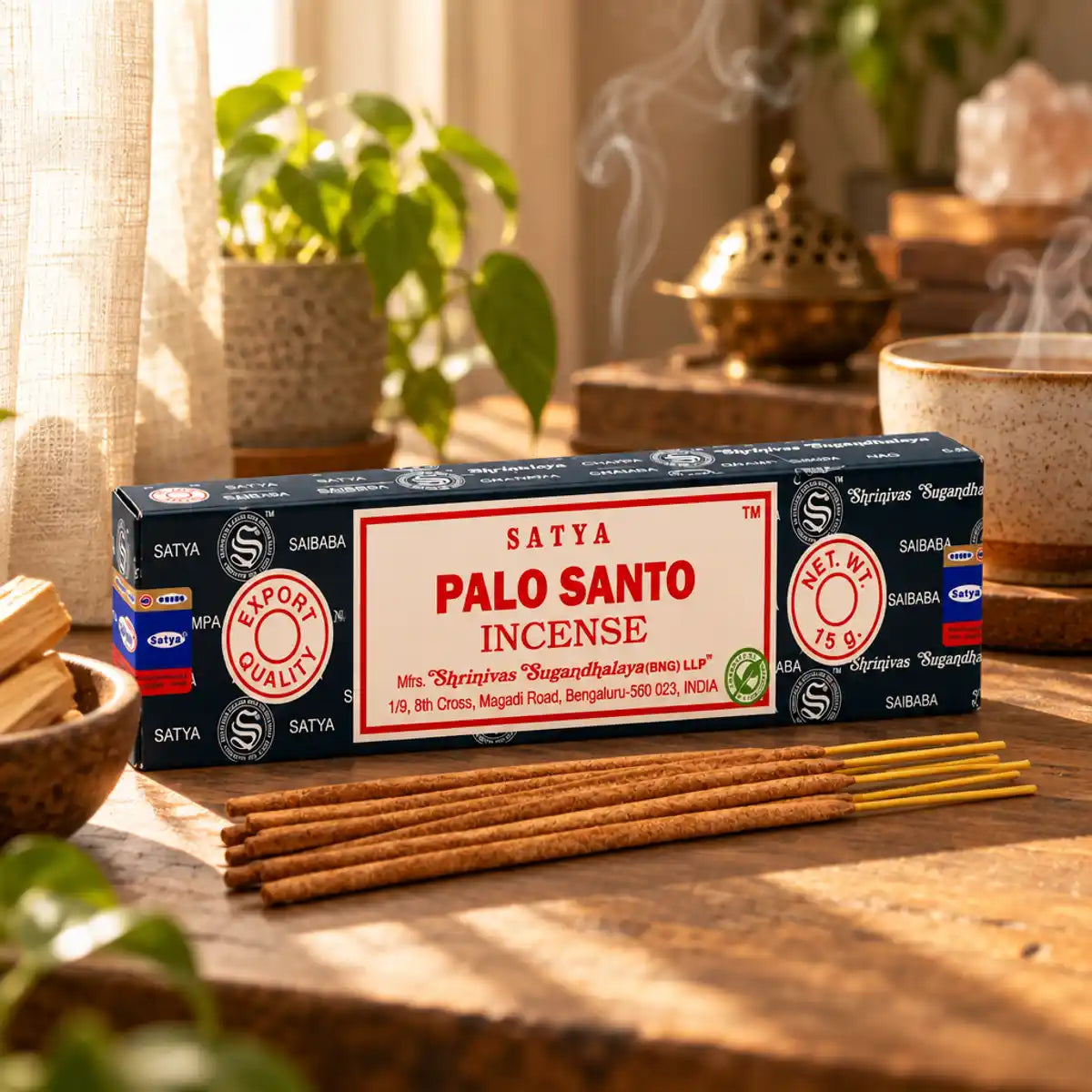 Encens Satya Palo Santo 15g en boîte bleu marine, posé sur une étagère en bois avec bâtonnets non allumés et fumée parfumée