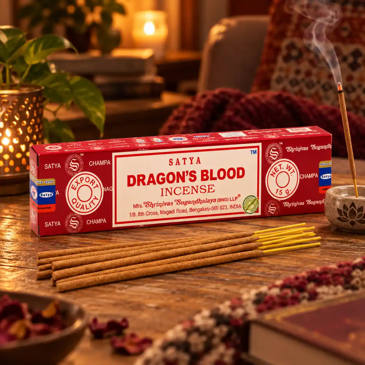 Encens Satya Sang de Dragon 15g : boîte rouge sur une table en bois, bâtonnets d'encens jaunes et fumée douce dans une ambiance chaleureuse