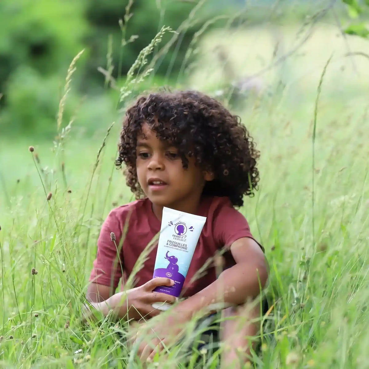 Enfant tenant le shampoing démêlant Frizouilles & Compagnie de Noire O Naturel