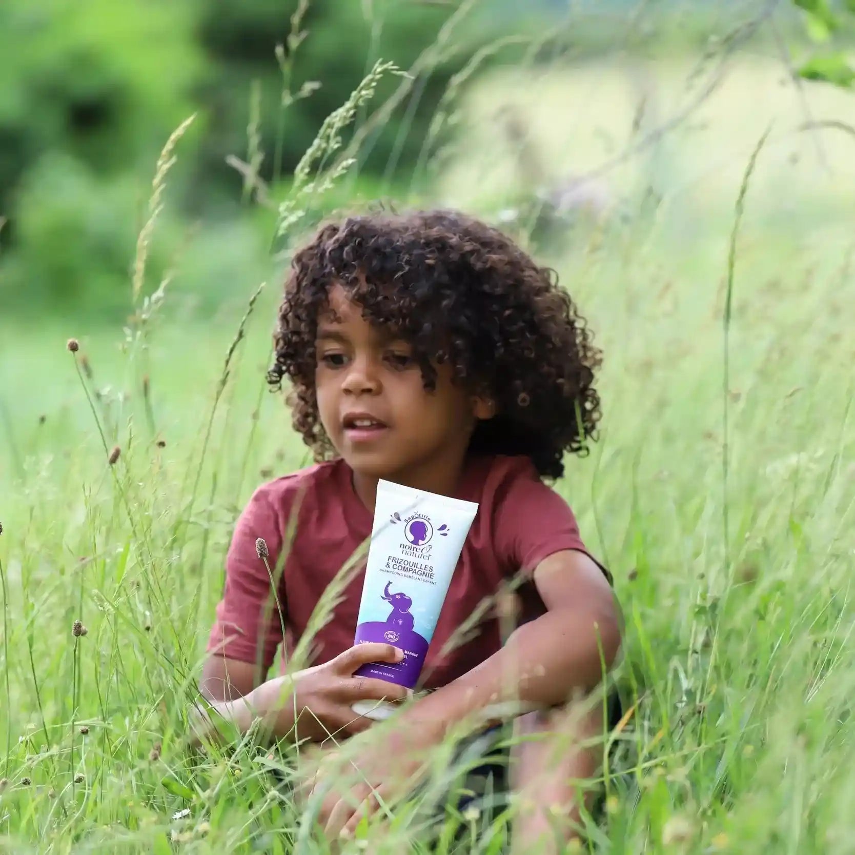Enfant tenant le shampoing démêlant Frizouilles & Compagnie de Noire O Naturel