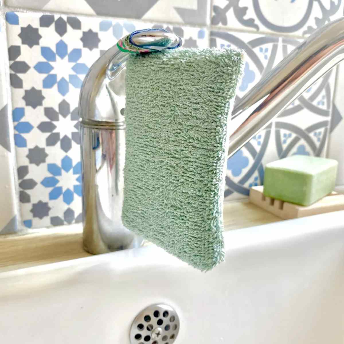 Eponge lavable verte Anotherway pendue au robinet pour séchage
