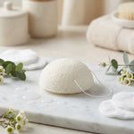Éponge Konjac blanche naturelle sur marbre pour douceur et éclat du teint