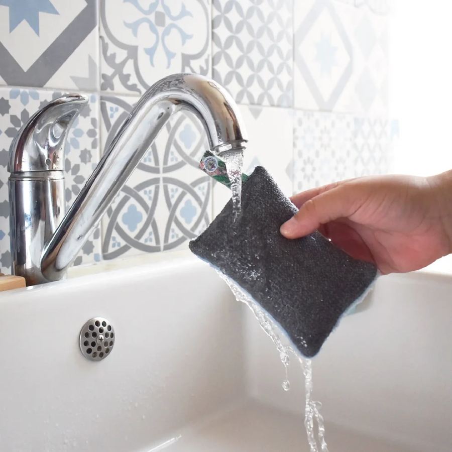 Eponge lavable et grattante bleue de la marque Anotherway sous un filet d'eau du robinet