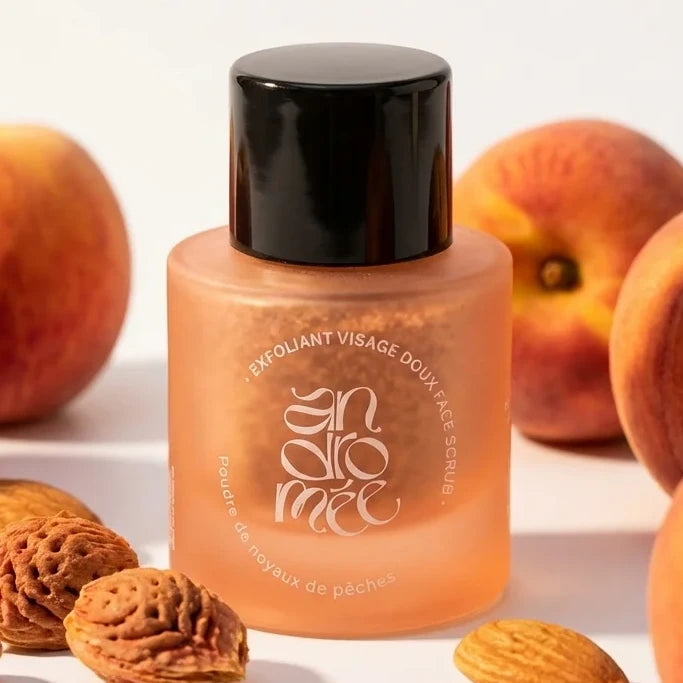 Exfoliant visage doux Andromée aux noyaux de pêches en flacon verre avec pêches fraîches
