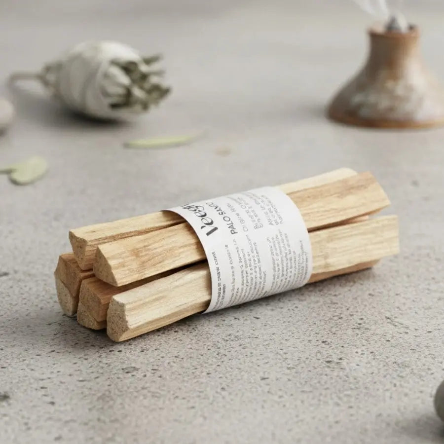 Un fagot de bâtons de palo santo de la maque Veegreen, sur une table en marbre beige, avec une sauge en arrière plan