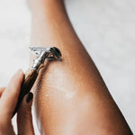 Une femme se rasant les jambes avec un rasoir en bambou de la marque bambaw