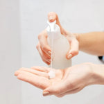 Main appuyant sur le flacon pompe de gel douche Pimpant, gel versé dans la paume de la main