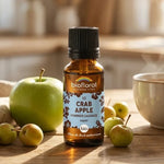 Flacon compte-gouttes ambré de fleur de Bach Crab Apple (pommier sauvage) Bio en granules, posé sur une table en bois avec une pomme verte et des crabes.