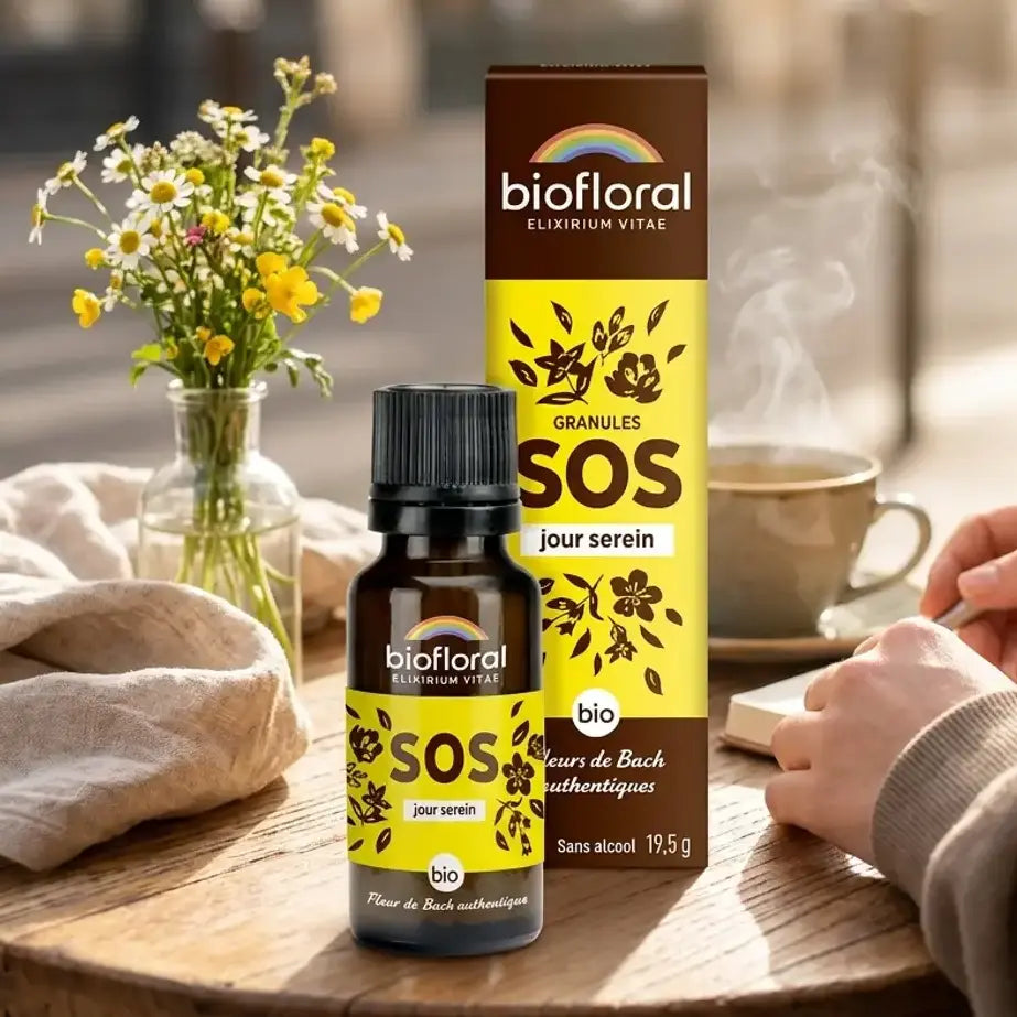 Flacon compte-gouttes ambre Biofloral SOS Jour Serein, fleurs de Bach bio en granules, sur table en bois avec tisane
