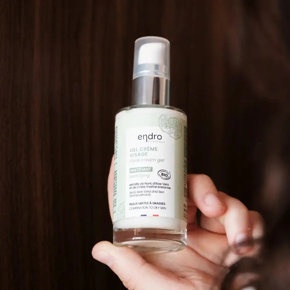 Un flacon de gel crème visage matifiant de la marque Endro tenu dans une main