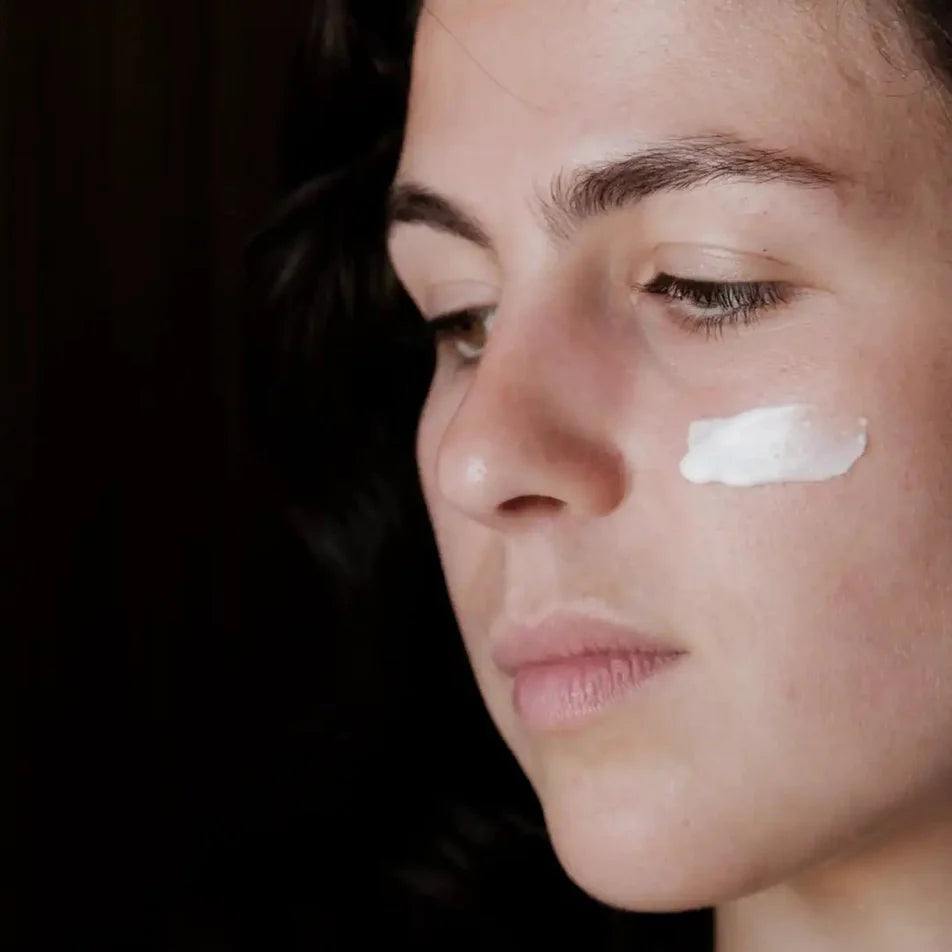Une femme avec un trait de crème hydratante sur la joue