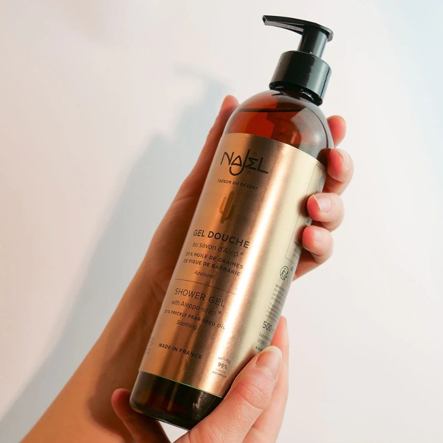 Une personne tenant un gel douche à l'huile de figue de barbarie de la marque Najel