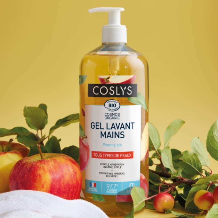 Un flacon pompe de Gel Lavant Mains Pomme certifié bio de 1L de Coslys posé à côté de pommes