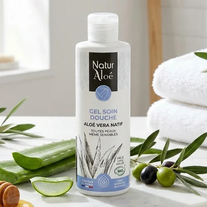 Gel soin douche bio Naturaloé 200ml entouré de feuilles d'aloe vera et de branches d'olivier sur marbre