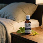 Flacon compte-gouttes ambré Gem-Nocte 11 Bio 50 ml Alphagem sur table de chevet, avec oreiller et plaid, ambiance apaisante du soir