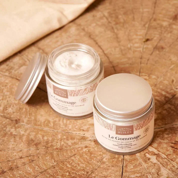Deux pots de gommages visage et corps de la marque Comptoir des Huiles sur du bois