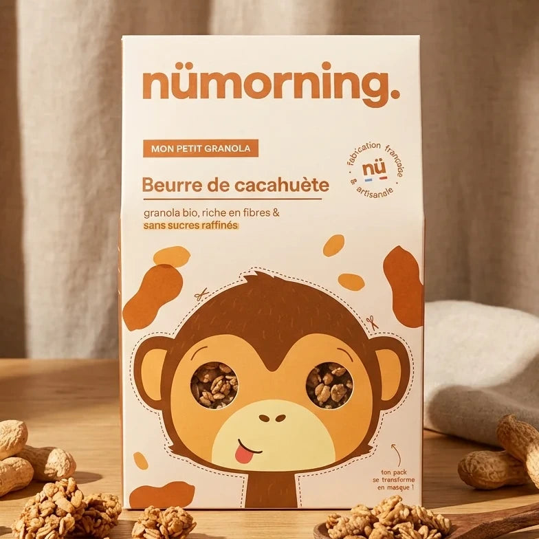 Granola Bio Beurre de Cachuète Nümorning sur table en bois avec cacahuètes et cuillère