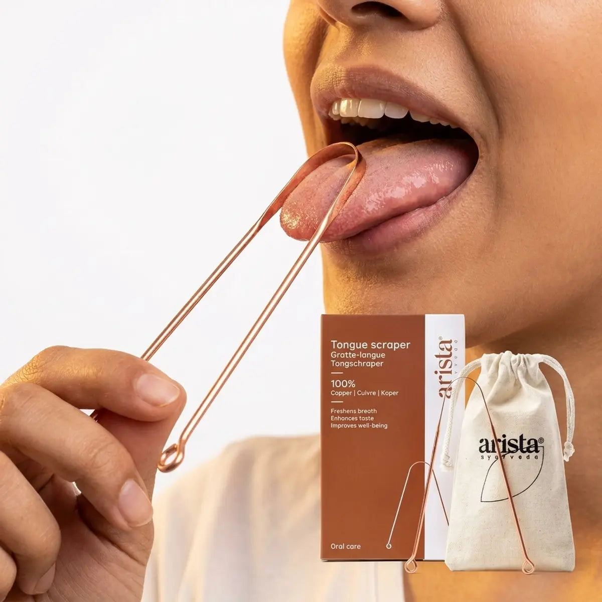 Gratte langue en cuivre Arista Ayurveda utilisé sur la langue, packaging et accessoires inclus