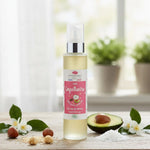 Un flacon d'huile capillaire en 100 ml de la marque Emma Noël posé sur une table avec des fleurs, des noix et de l'avocat