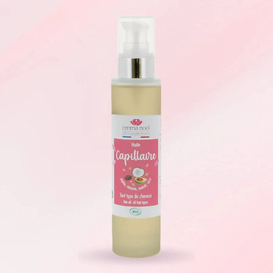 Un flacon d'huile capillaire en 100 ml de la marque Emma Noël sur un fond rose