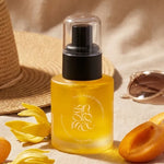 Huile corps Abricot & Ylang Ylang Andromée 30ml avec fleurs et tranches d'abricot sur fond beige