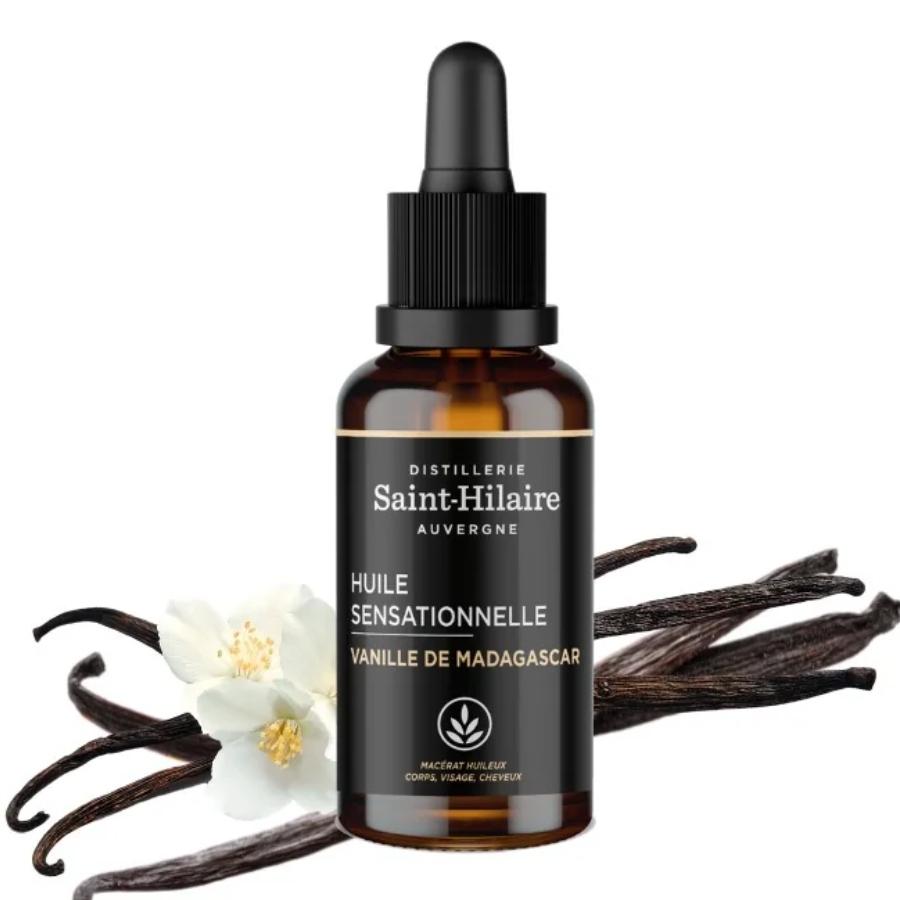 Un flacon de 30ml d'huile de macération à la vanille de Madagascar de la distillerie Saint-Hilaire accompagné de gousse de vanille en arrière plan. 