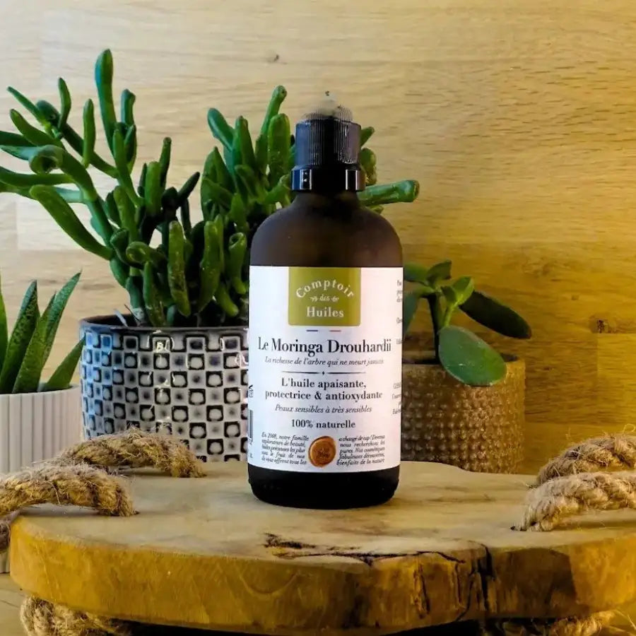 Un flacon d'Huile de Moringa Drouhardii Bio 100 ml Comptoir des Huiles posé sur un rondin en bois