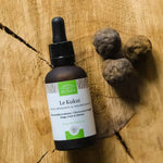 Une huile de kukui de la marque comptoir des huiles avec des noix sur un tronc d'arbre