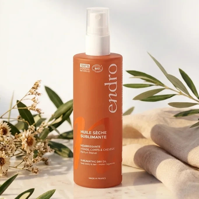Huile sèche sublimante Endro 100ml sur surface marbre avec botaniques et éclairage doré
