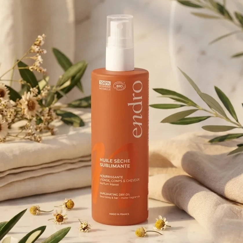 Flacon Huile Sèche Sublimante Endro 100ml entouré de serviettes et plantes naturelles sur marbre blanc